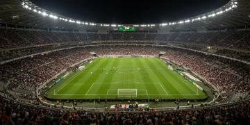 Estádio de futebol lotado com painéis de patrocínio digital reluzentes, simbolizando a crescente valorização dos acordos no futebol brasileiro.