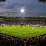 Estádio de futebol lotado ao entardecer, simbolizando a recuperação e o sucesso de um clube após uma crise.