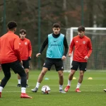 Jovens atletas em treinamento intenso em uma academia de futebol de base, com foco no desenvolvimento técnico e tático.
