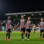 Base Forte: 10 jovens talentos que impulsionaram 20% mais pontos na Série B Jovens jogadores de futebol comemorando um gol em campo profissional, simbolizando o sucesso da base no futebol brasileiro.