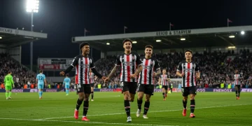 Jovens jogadores de futebol comemorando um gol em campo profissional, simbolizando o sucesso da base no futebol brasileiro.