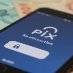 Smartphone com o logo do Pix e notificação de transação segura, com notas de real desfocadas ao fundo.
