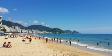 Praia ensolarada no Brasil com pessoas aproveitando o calor do verão de 2025 e o mar calmo.