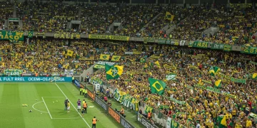 Torcedores brasileiros em um estádio lotado, celebrando a paixão pelo futebol e suas superstições.