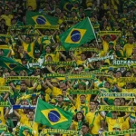 Torcida brasileira vibrante em um estádio de futebol, com bandeiras e fumaça colorida