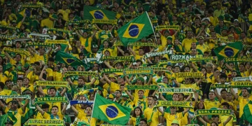 Torcida brasileira vibrante em um estádio de futebol, com bandeiras e fumaça colorida