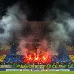 Torcida vibrante em estádio brasileiro com mosaico e bandeiras coloridas, celebrando a paixão pelo futebol em 2025.