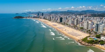 Vista aérea de uma cidade praiana brasileira vibrante, com turistas desfrutando do sol e mar, simbolizando crescimento econômico e atratividade internacional.