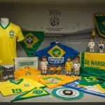 Coleção vibrante de itens históricos e atuais da Seleção Brasileira de futebol, exibindo camisas, flâmulas e miniaturas, com o ano de 2026 ao fundo.