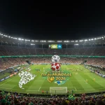 Estádio lotado e iluminado, com o placar exibindo 'Copa do Mundo 2026' e bandeiras sul-americanas vibrando.
