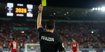 Árbitro de futebol mostrando cartão amarelo a jogador, simbolizando as novas regras de arbitragem no Brasil a partir de 2026 e seus impactos.