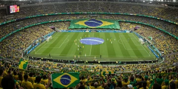 Estádio brasileiro lotado, torcida vibrando com bandeiras do Brasil e camisas amarelas, simbolizando a paixão e o orgulho nacional pelo futebol.