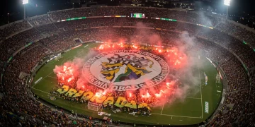 Torcida organizada brasileira em estádio lotado, celebrando com bandeiras e fumaça colorida, simbolizando a paixão do futebol.